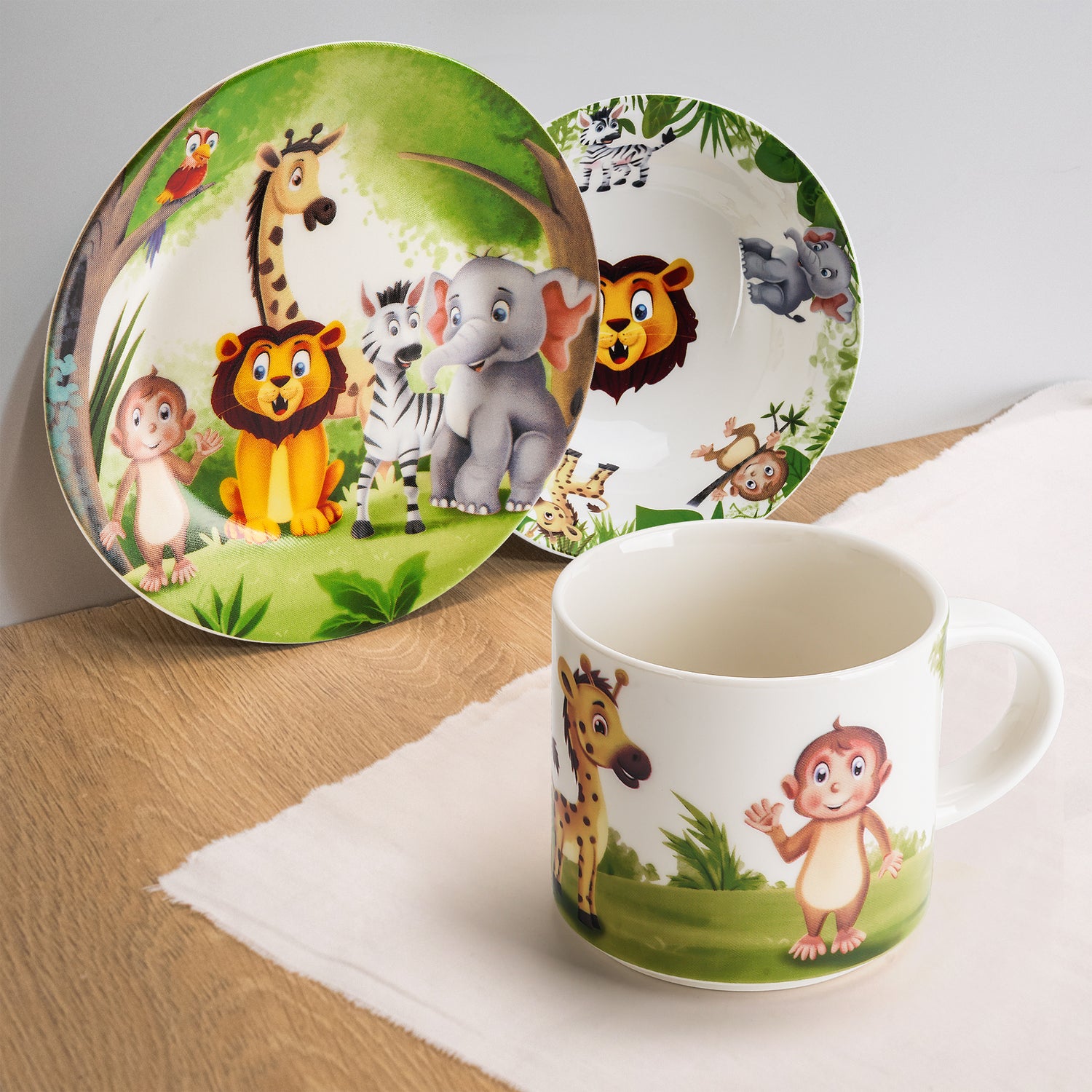 MIAMIO 3er-Set Kindergeschirr Jungle Aufdruck auf einem Holztisch mit Tuch