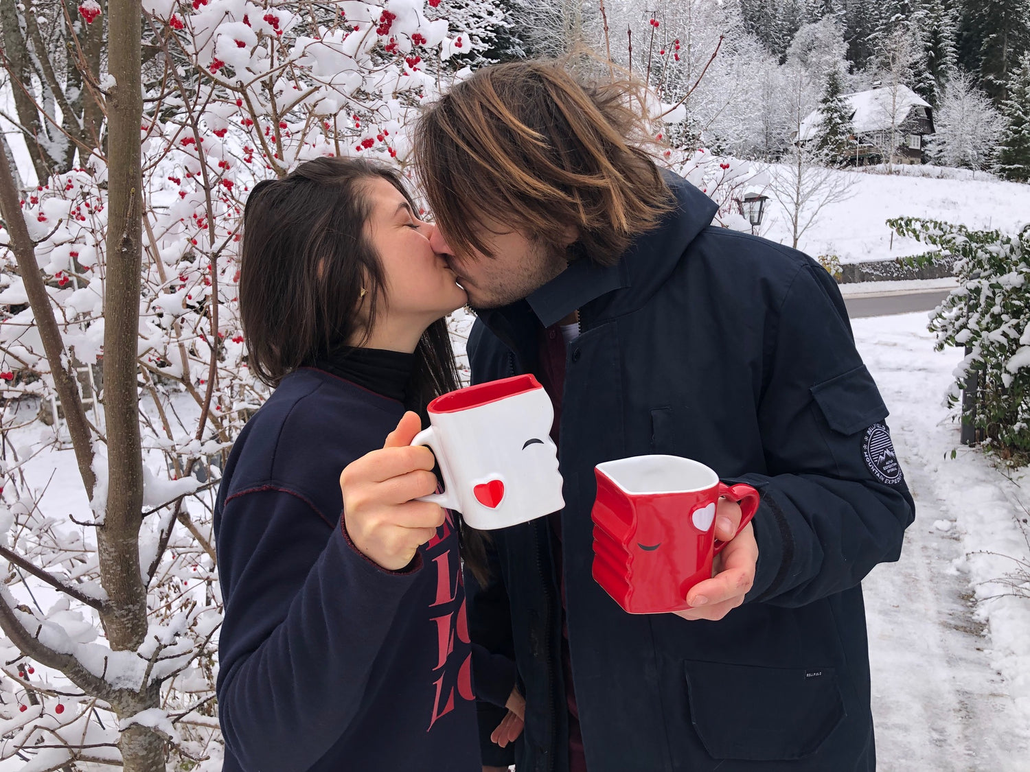 Ein küssendes Paar im Schnee mit MIAMIO küssenden Tassen Set für zwei Personen in Rot